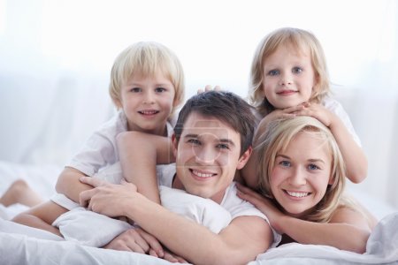 A family with two children on a bed in the bedroom