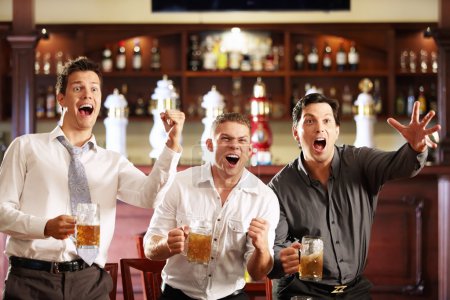 Young men rejoice the victory of his team in a bar