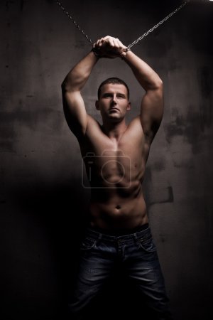 Young male model well build with chains over his arms
