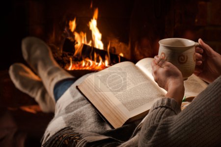 Woman reads book near fireplace