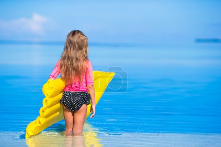Adorable girl with inflatable air mattress in outdoor swimming pool