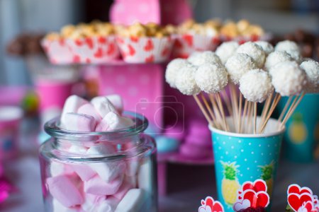 Marshmallow, sweet colored meringues, popcorn, custard cakes and cake pops on table