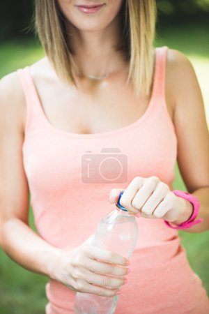 Beautiful young fitness woman holding water after working out
