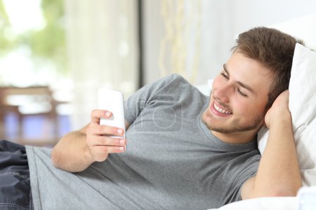 Relaxed man using a smart phone at home