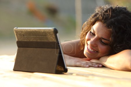 Woman watching videos on a tablet at sunset