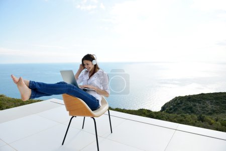 Woman working on laptop in headphones