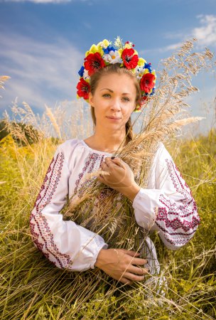 ukrainian woman in embroidered shirt holding sheaf of wheat