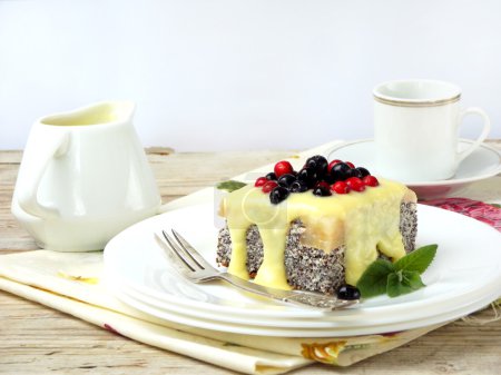 cottage cheese and poppy cheesecake with blueberries, cranberries poured on yellow vanilla sauce. cake on light background. selective focus