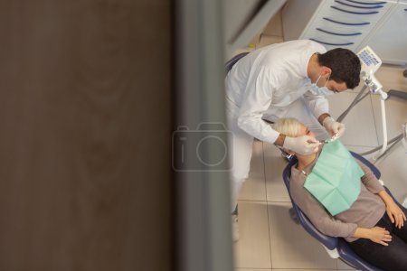 top view of caucasian dentist doing his job on a young blonde wo