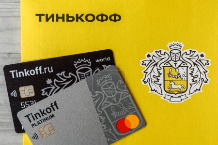 Moscow, Rissia - February 11, 2021: Bitcoin, Black and Platinum Tinkoff Bank debit card and corporate yellow envelope (text translation from russian: Tinkoff). Russian commercial bank founded by Oleg Tinkov.