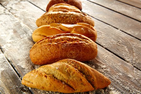 Breads varied in a row on rustic wood and flour