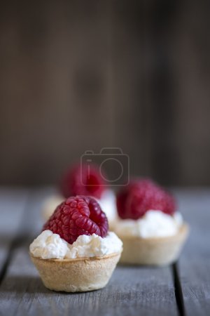 Raspberry tartlets on rustic wooden kitchen  background