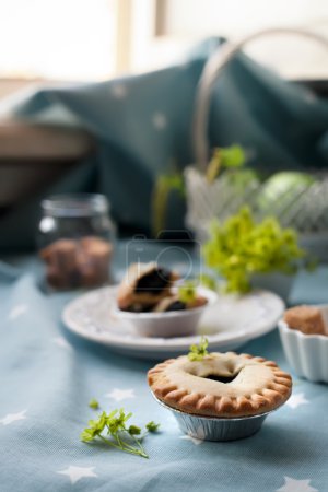 Blueberry tart set with apples and sugar by a window.