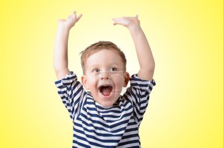 little boy with his hands up smiling on yellow background