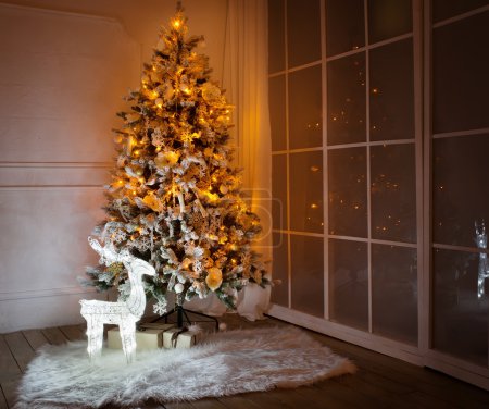 A lighted Christmas tree with presents underneath in living room