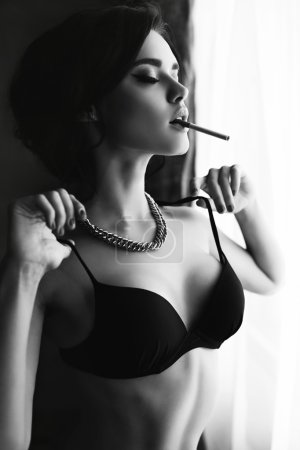 beautiful sexy girl with dark hair wears lingerie,smoking beside a window 