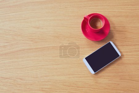 Smartphone with coffee cup on table