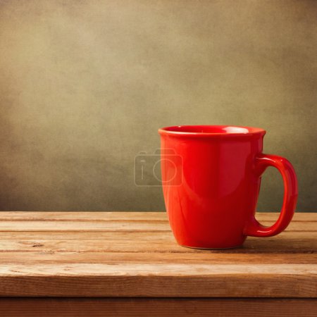 Coffee cup on wooden table over grunge background