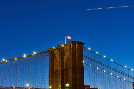 Close up of a pillar of the Brooklyn bridge with flag at night