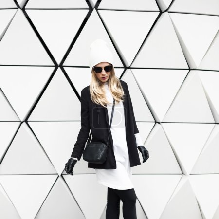 Glamorous blonde standing at the wall. Urban fashion black and w