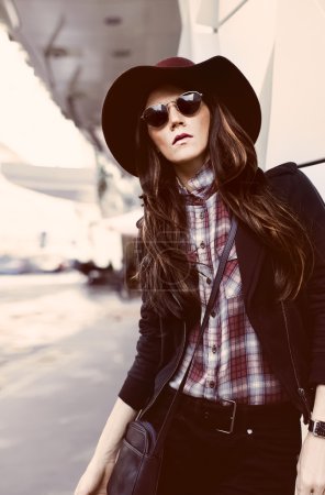 Girl in vintage hat and sunglasses on a city street. fashion sty