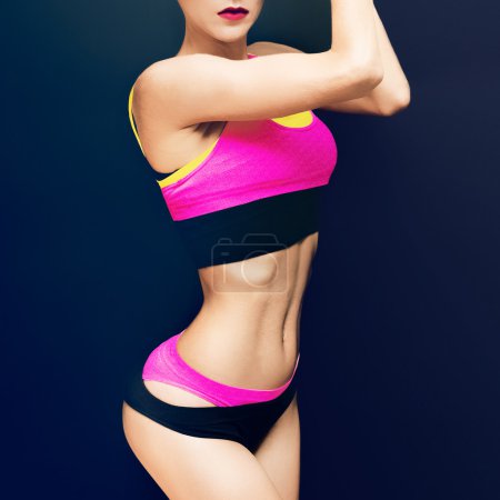 Slim athletic fitness blonde on a black background in the fashio