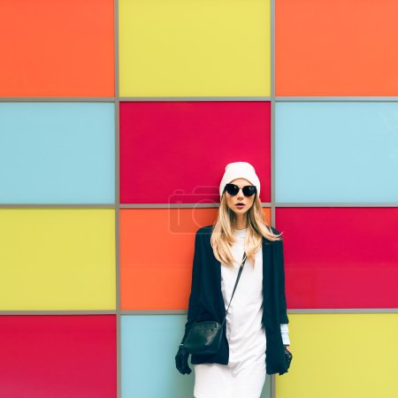 Fashionable blonde standing against a bright wall. urban style