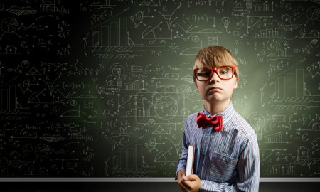 Genius boy near blackboard with formulas