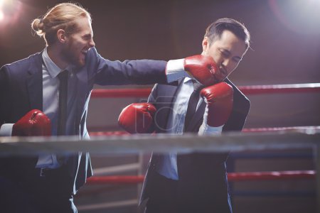 Businessman in  boxing gloves attacking rival