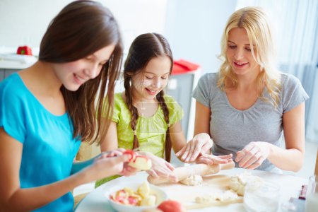 Girls preparing food with mother