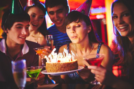 Girl blowing on candles on birthday cake