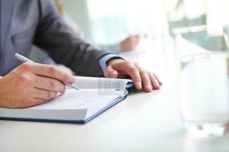 Hand of businessman writing in notebook