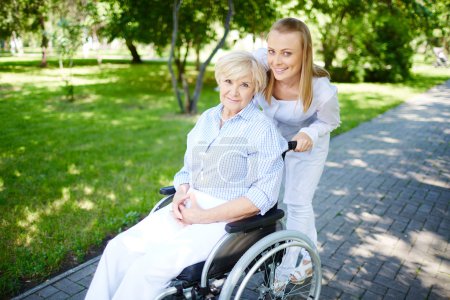 Female caregiver walking with senior patient