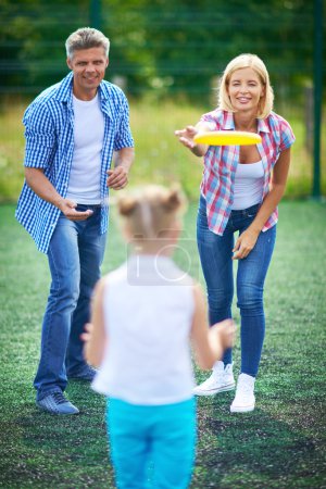 Parents playing frisbee with daughter