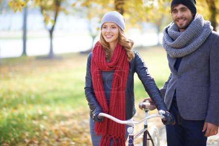 Couple with bicycle in autumn park