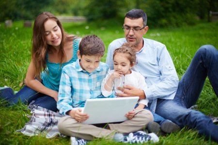 Family using laptop in park