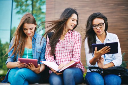 Teenage girls reading outside