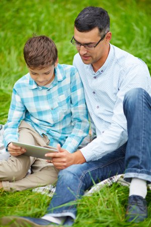 Father and son using digital tablet outdoors
