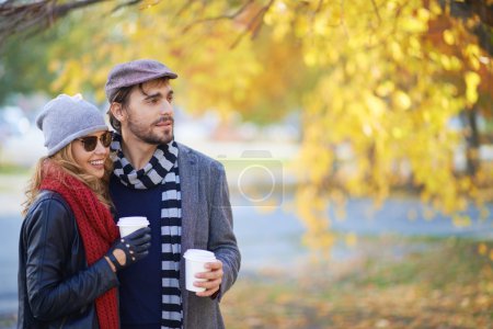 Couple drinking coffee in autumn park