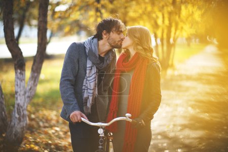 Couple with  bicycle kissing in park