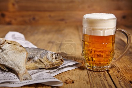 Beer and dried fish on wooden table