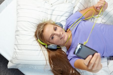 Woman lying on bed while listening music