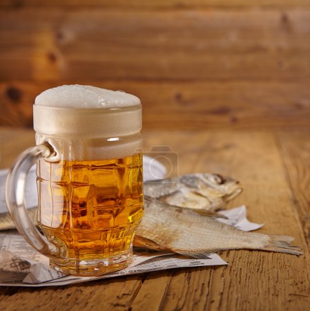 Beer and dried fish on wooden table