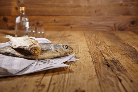 Vodka and dried fish on wooden table