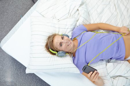 Woman lying on bed while listening music