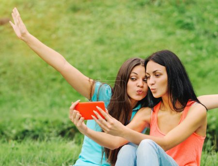 two women friends taking pictures of themselves with smart phone