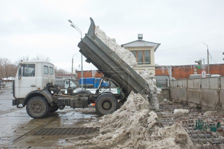 Unloading dirty snow from the body of the dump truck MAZ in negotable on snow-melting point, Moscow