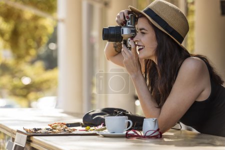 young beautiful traveler happily taking photos with camera at ca