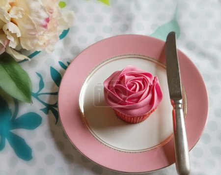 Overhead of pink rose frosted cupcake on vintage plate