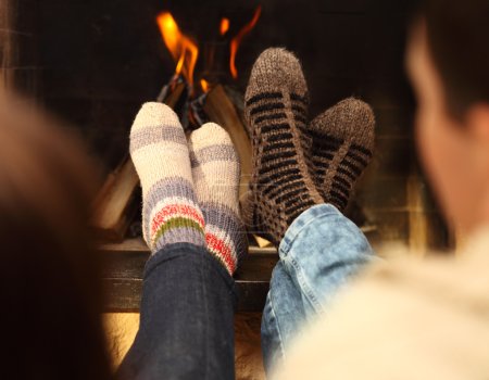 Legs of a couple in socks in front of fireplace at winter season